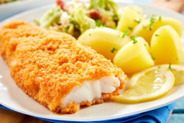 Crispy breaded fish with potatoes in close up Close up view of crispy breaded fish served on plate with potatoes